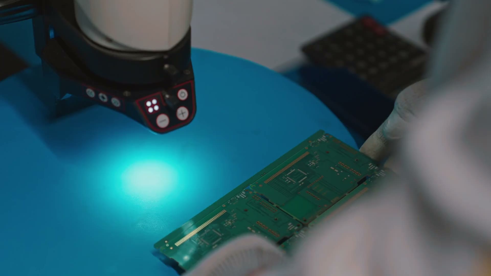 Board inspection at the Noida plant, gloved operator under a digital microscope